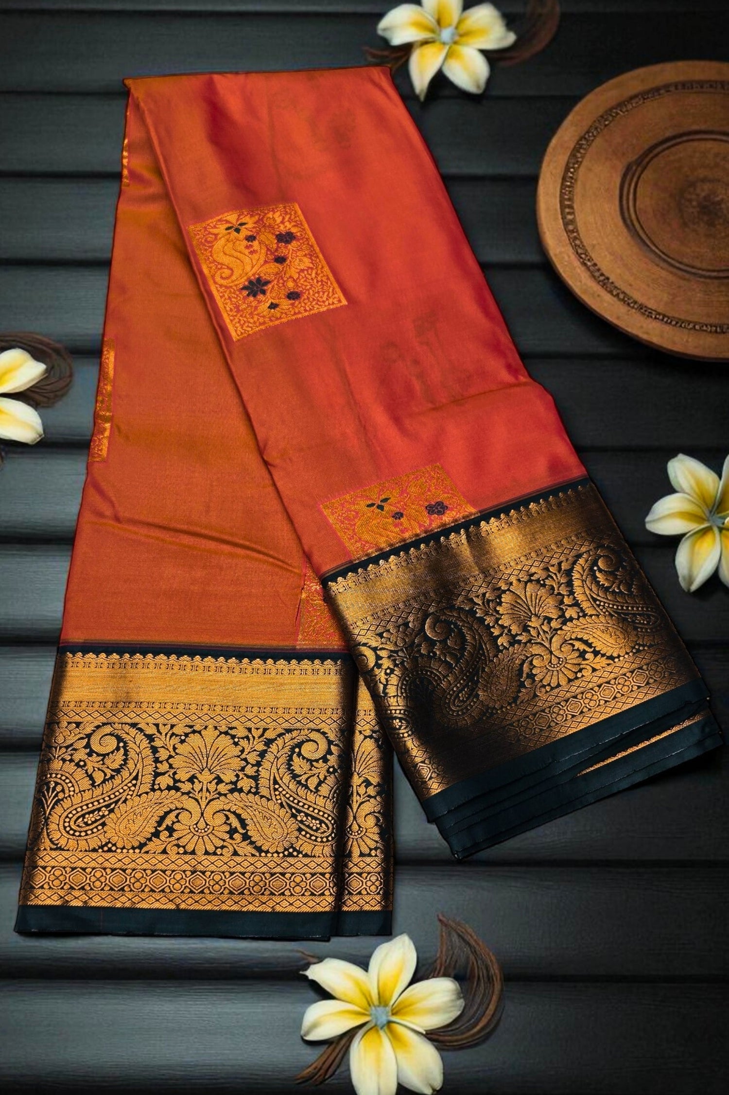 Orange saree with gold and black patterns on a dark background