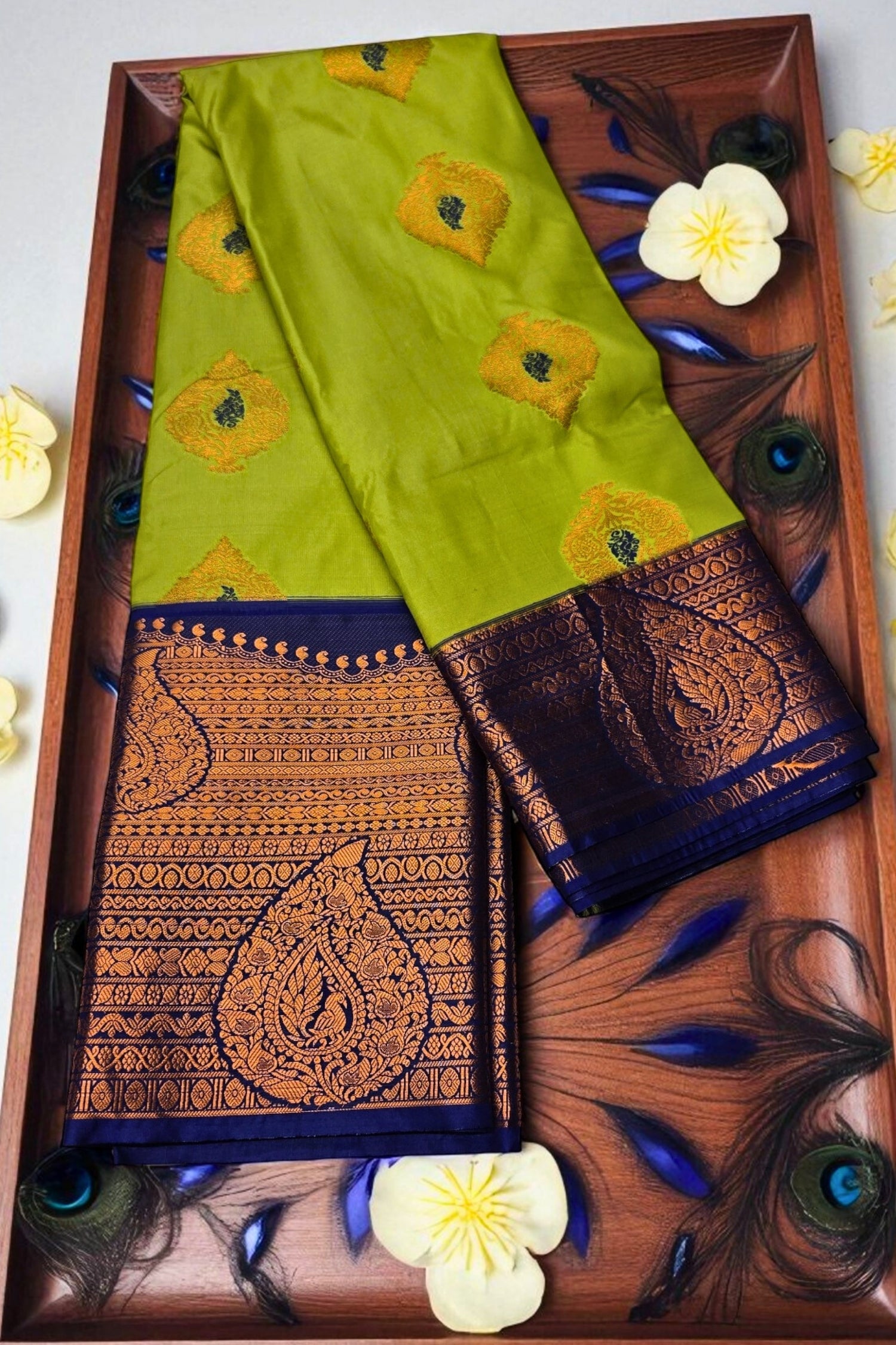 Green saree with gold and blue patterns on a wooden tray