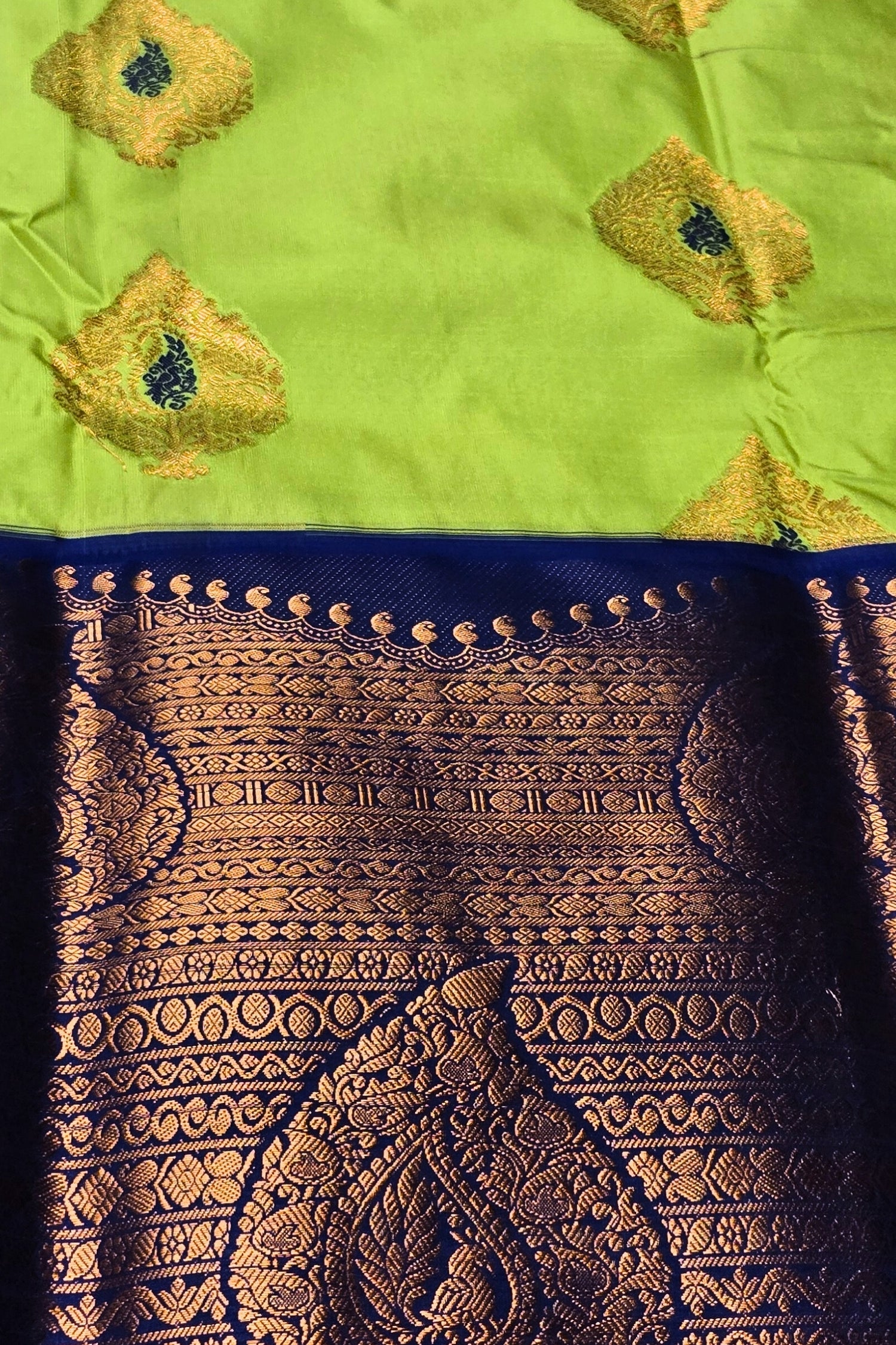 Traditional saree with intricate gold patterns on a green and blue background