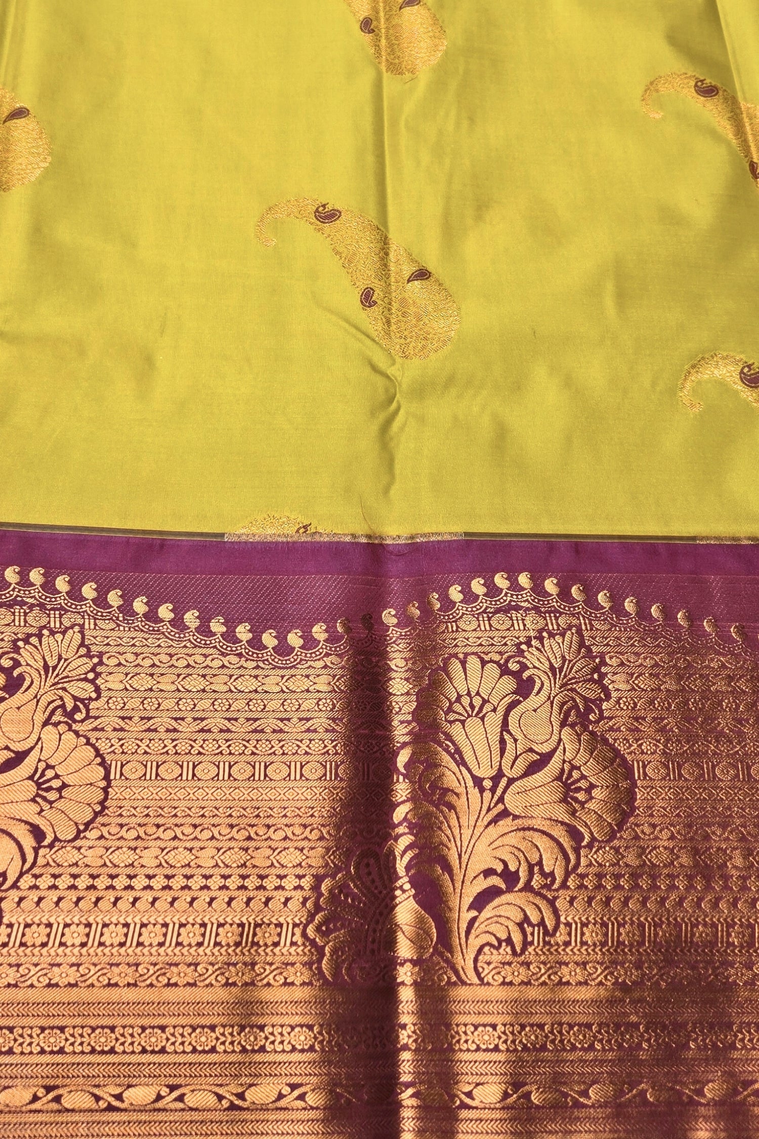 Traditional saree with green fabric and purple border featuring gold patterns