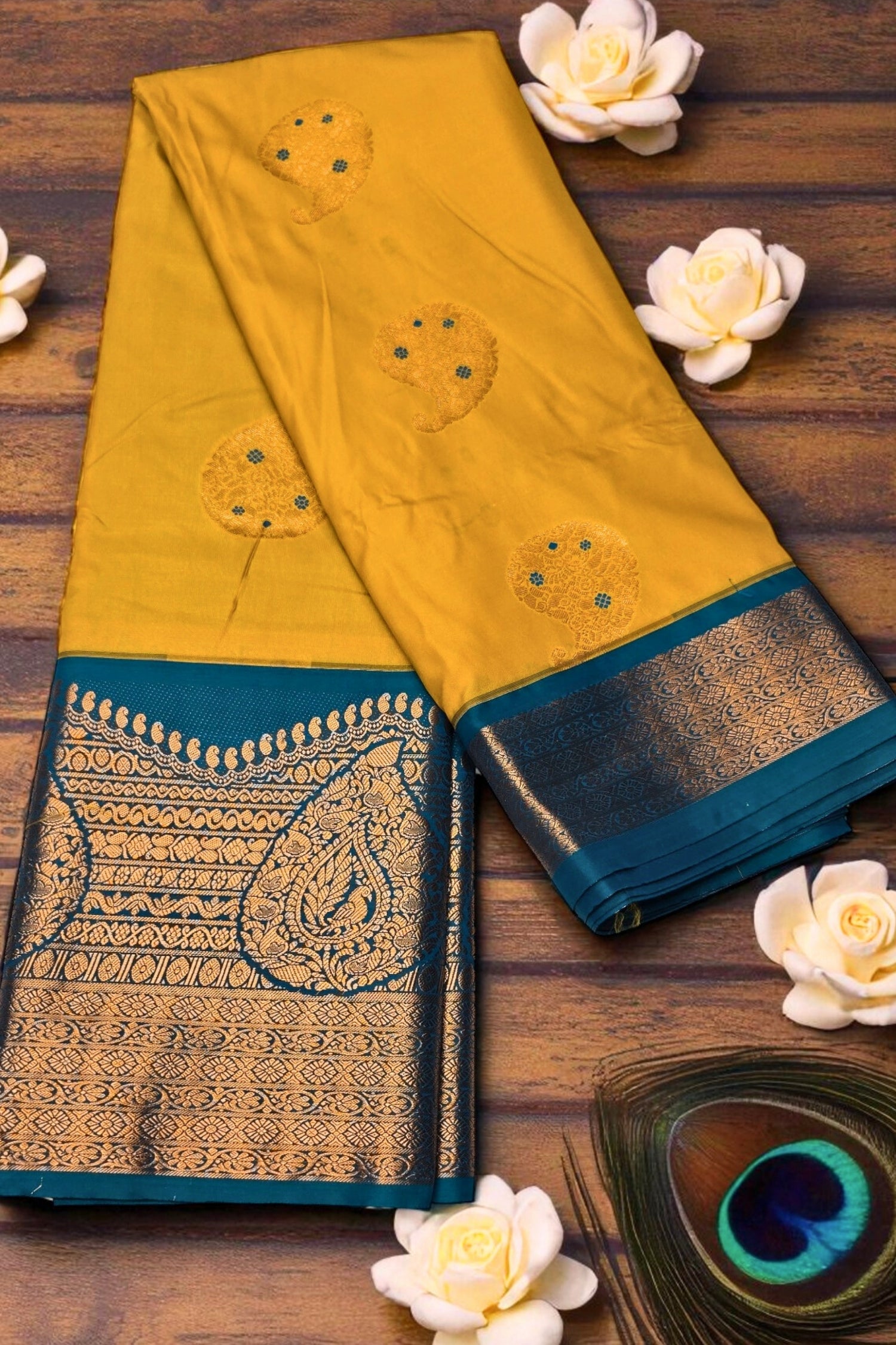 Yellow saree with blue border on a wooden surface with white flowers.