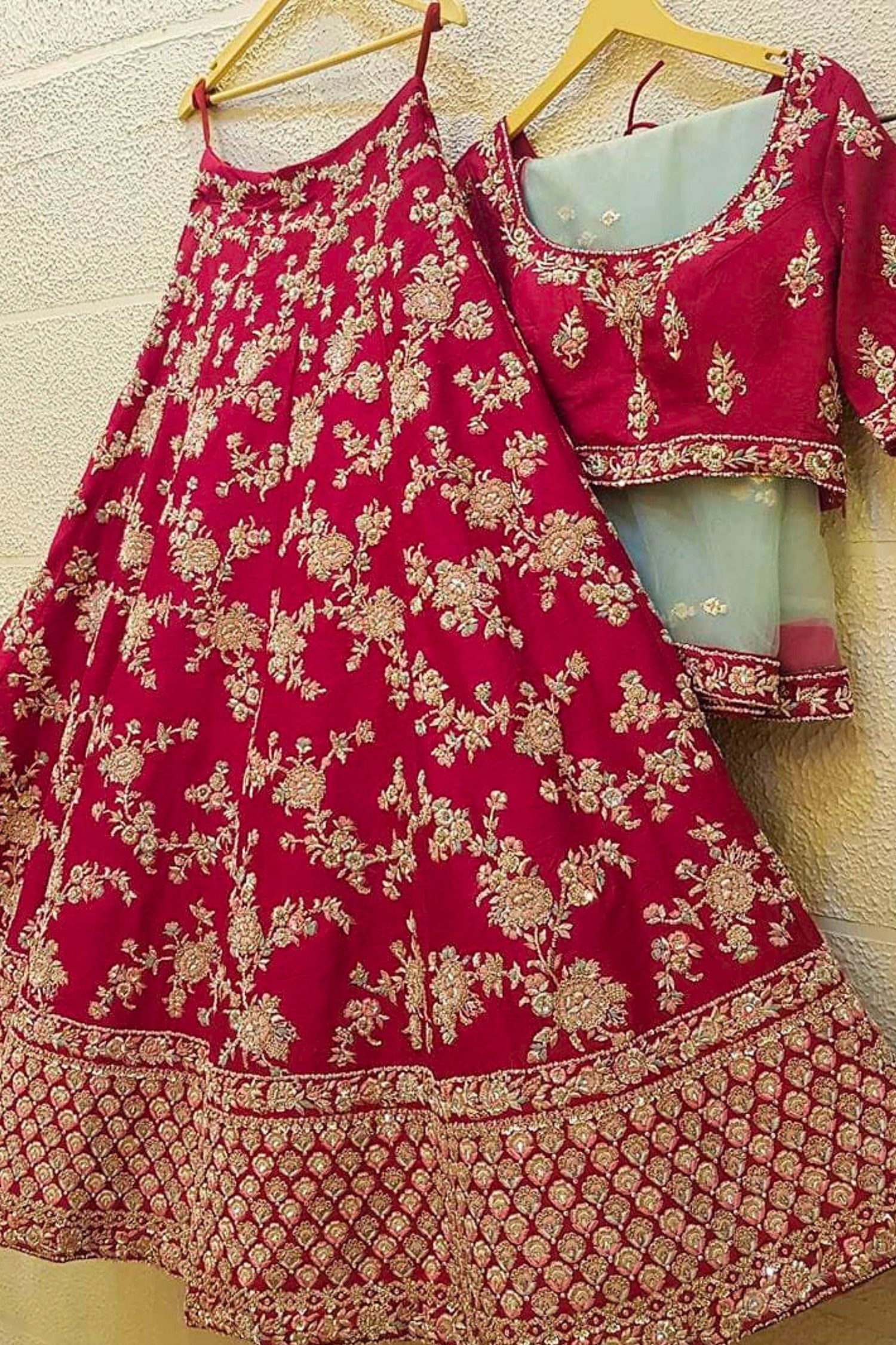 Red traditional outfit with floral patterns on a wooden hanger against a light background