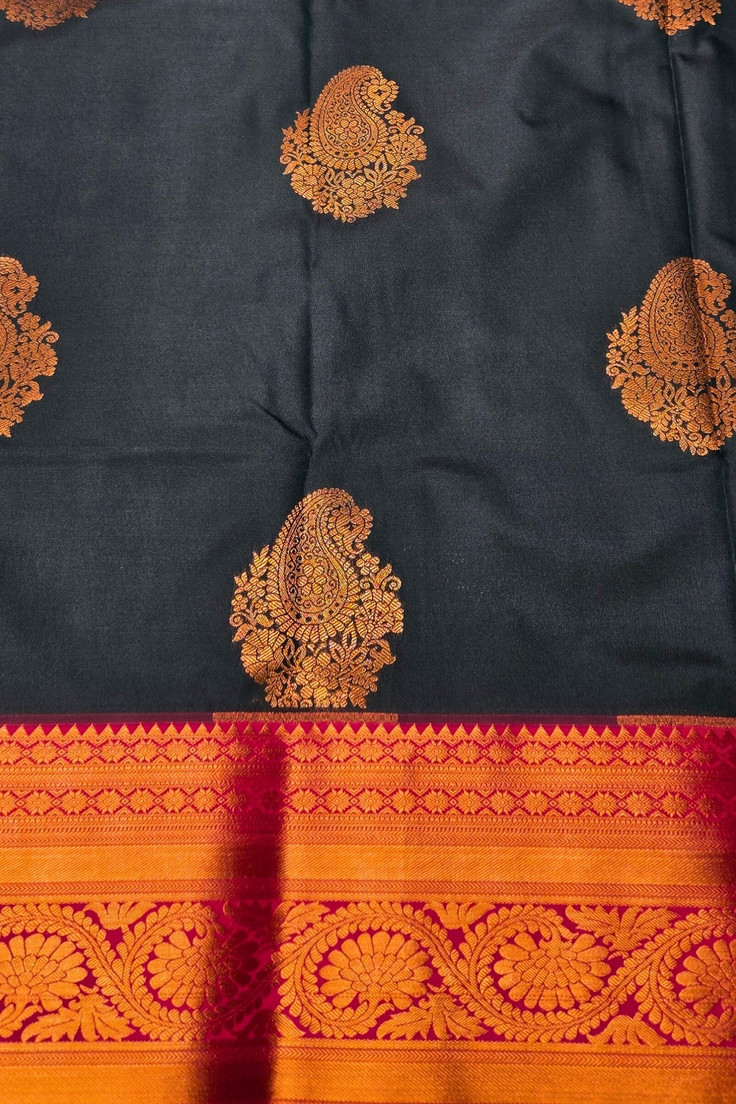 Black fabric with orange paisley patterns and a red border