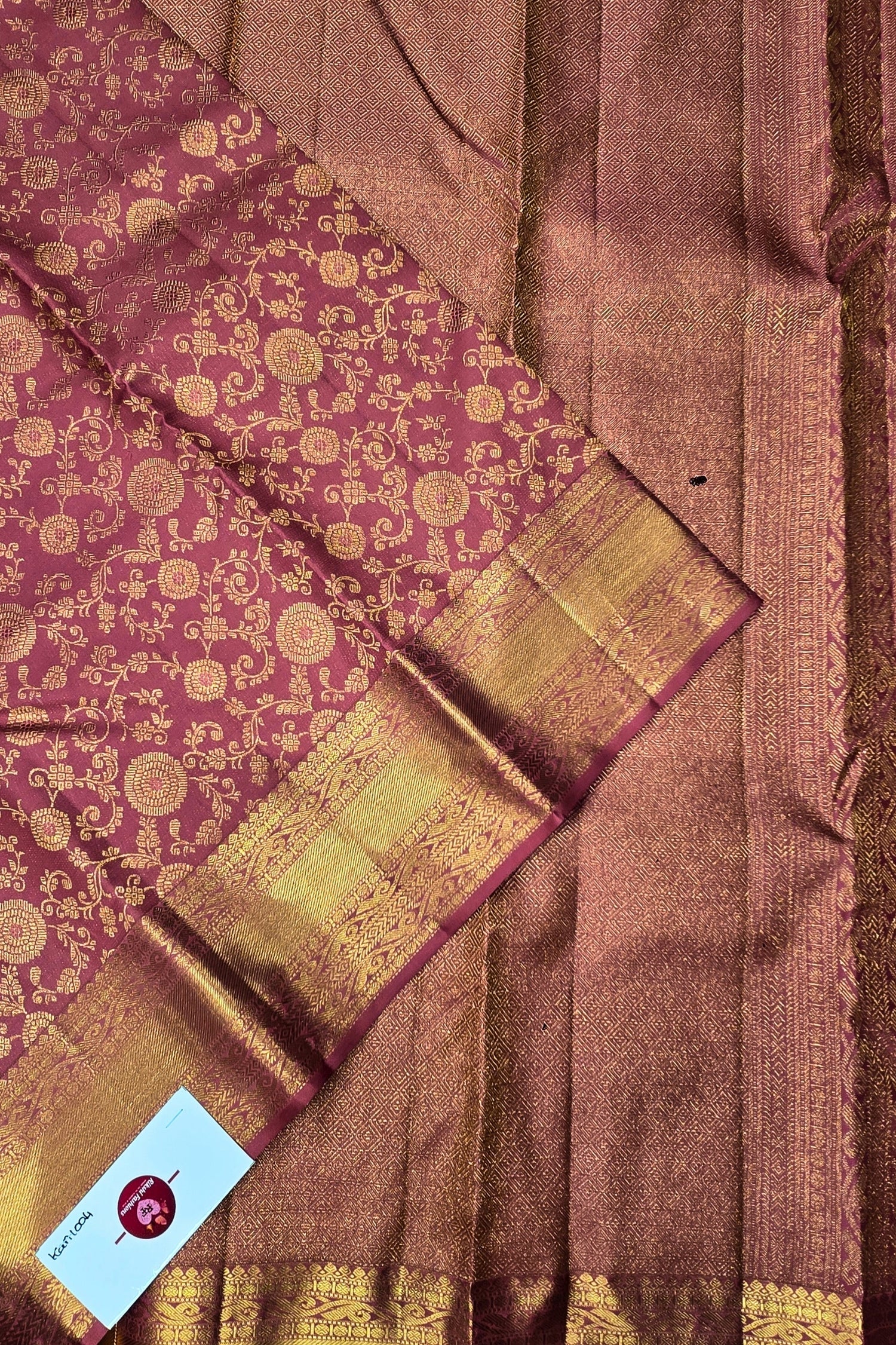 Brown and gold traditional saree with a visible brand label.