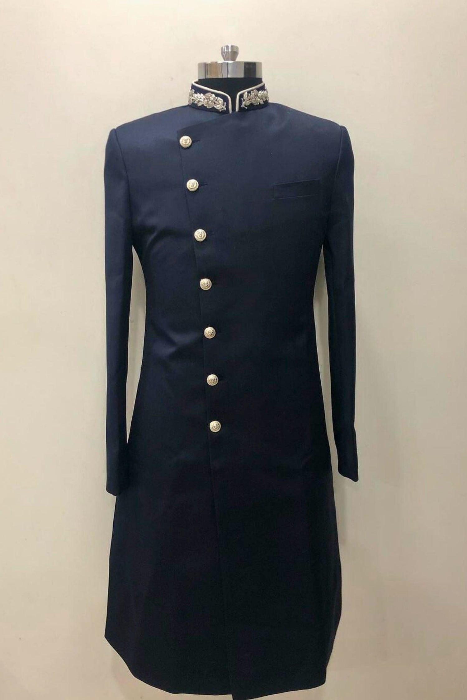 Navy blue formal coat with white buttons on a mannequin against a beige background