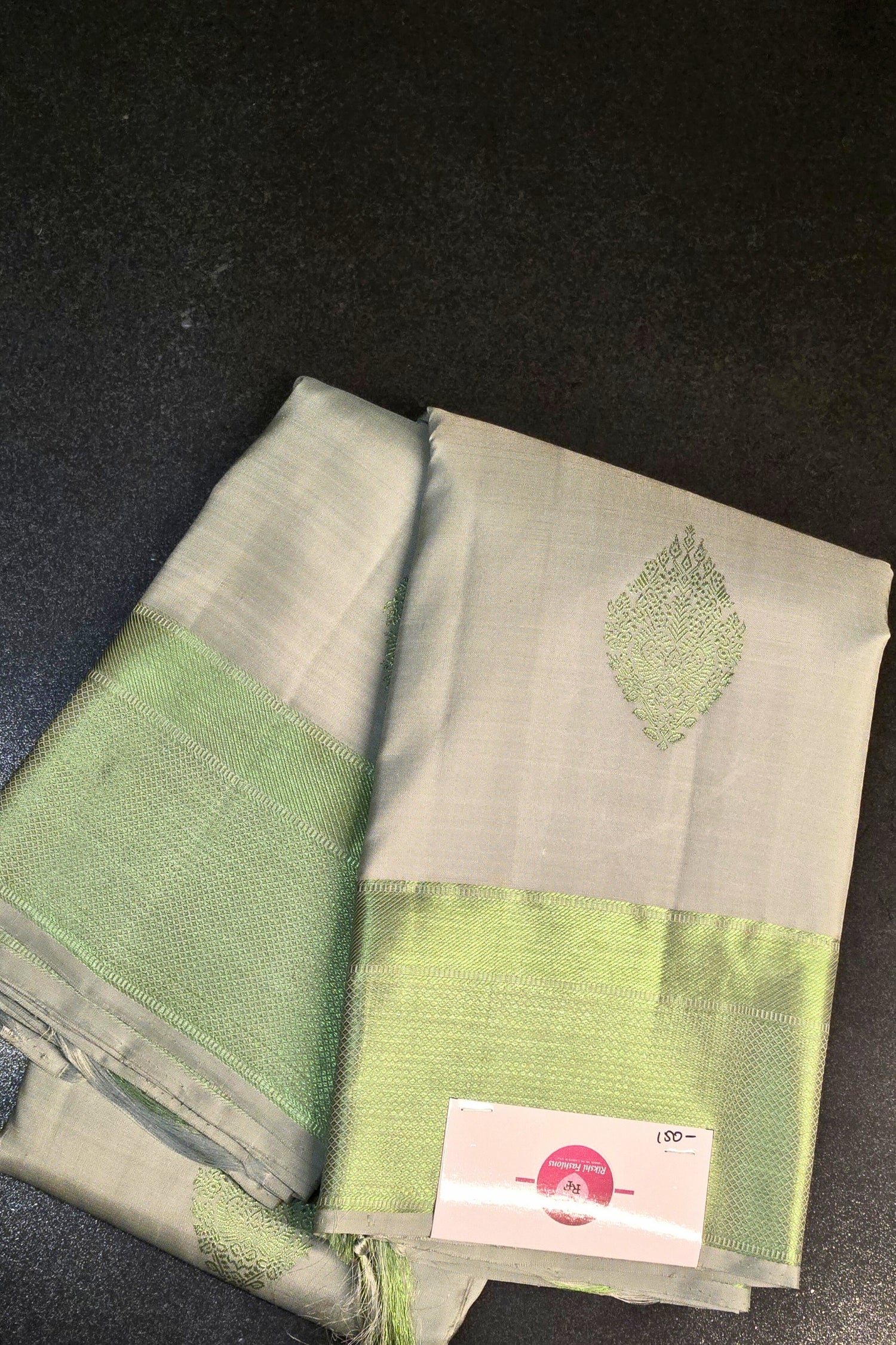 White silky Kanchipuram saree with light zari border displayed on mannequin