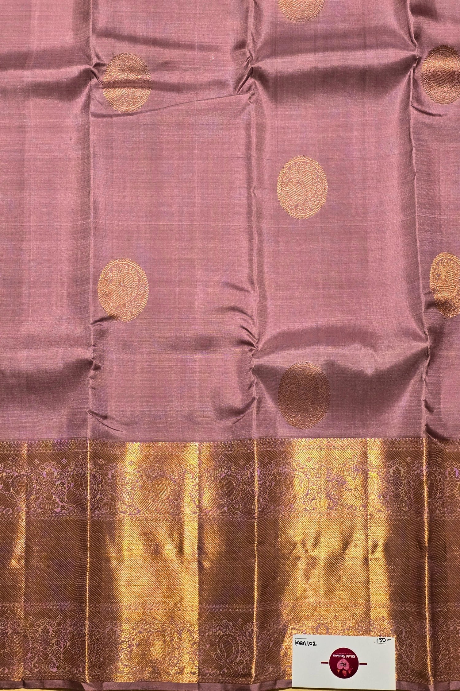 Pink saree with gold patterns and a brand label in the corner