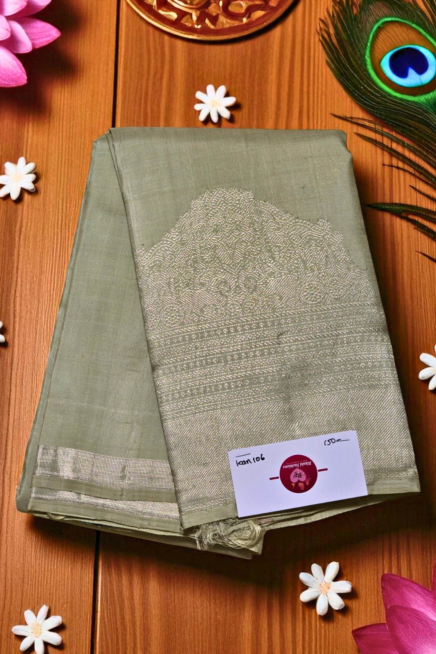 Green saree with silver border on a wooden surface with decorative elements