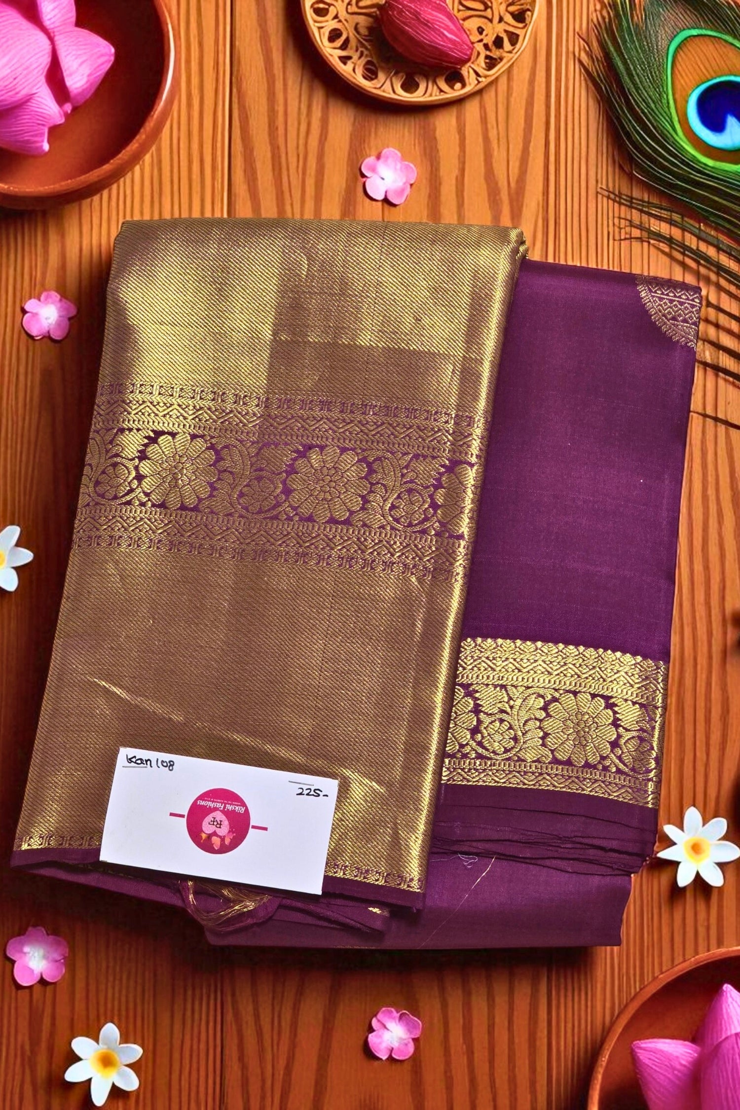 Purple and gold saree with a brand label on a wooden surface with decorative elements.