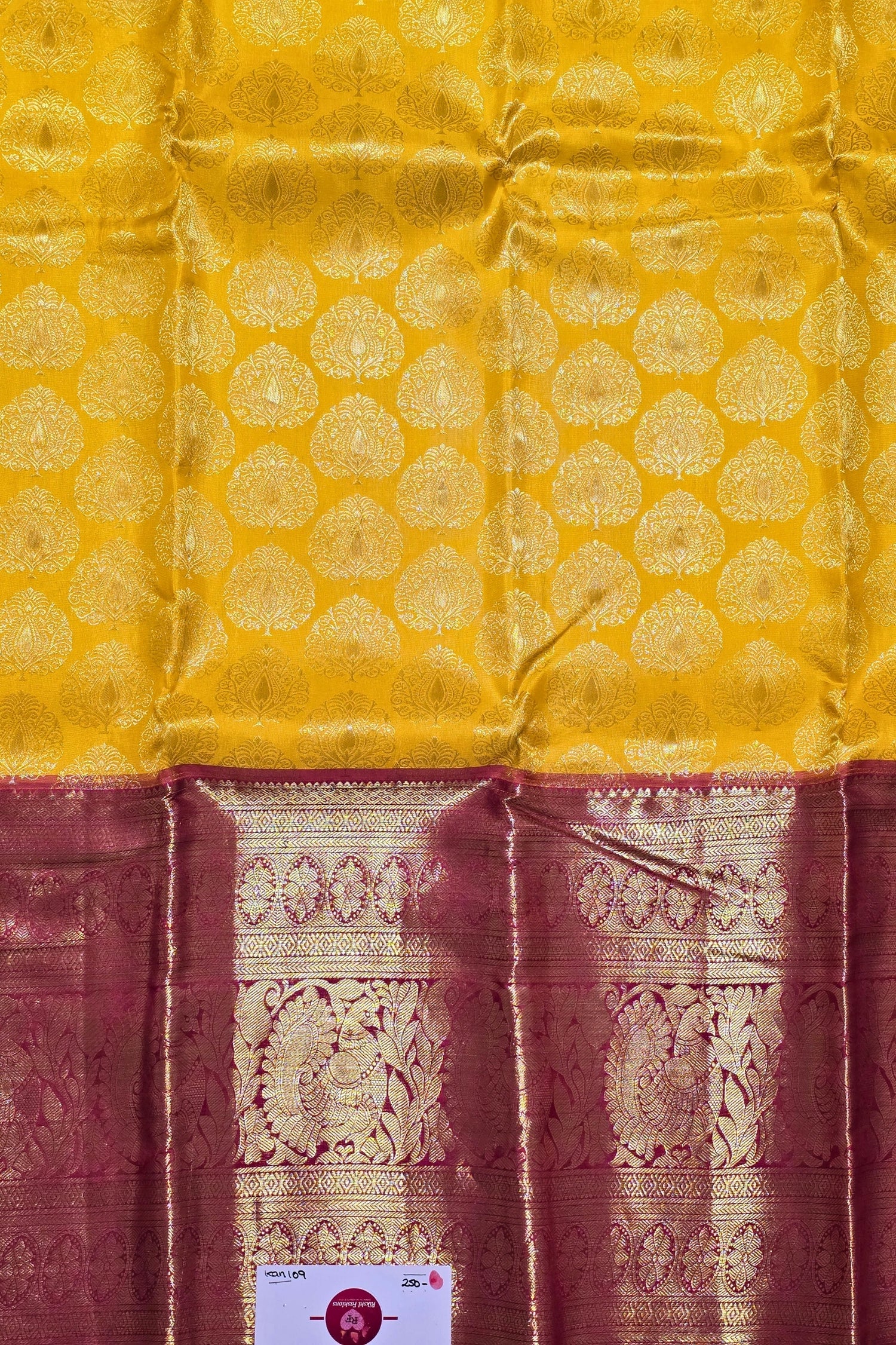 Yellow fabric with intricate gold patterns and a maroon border.