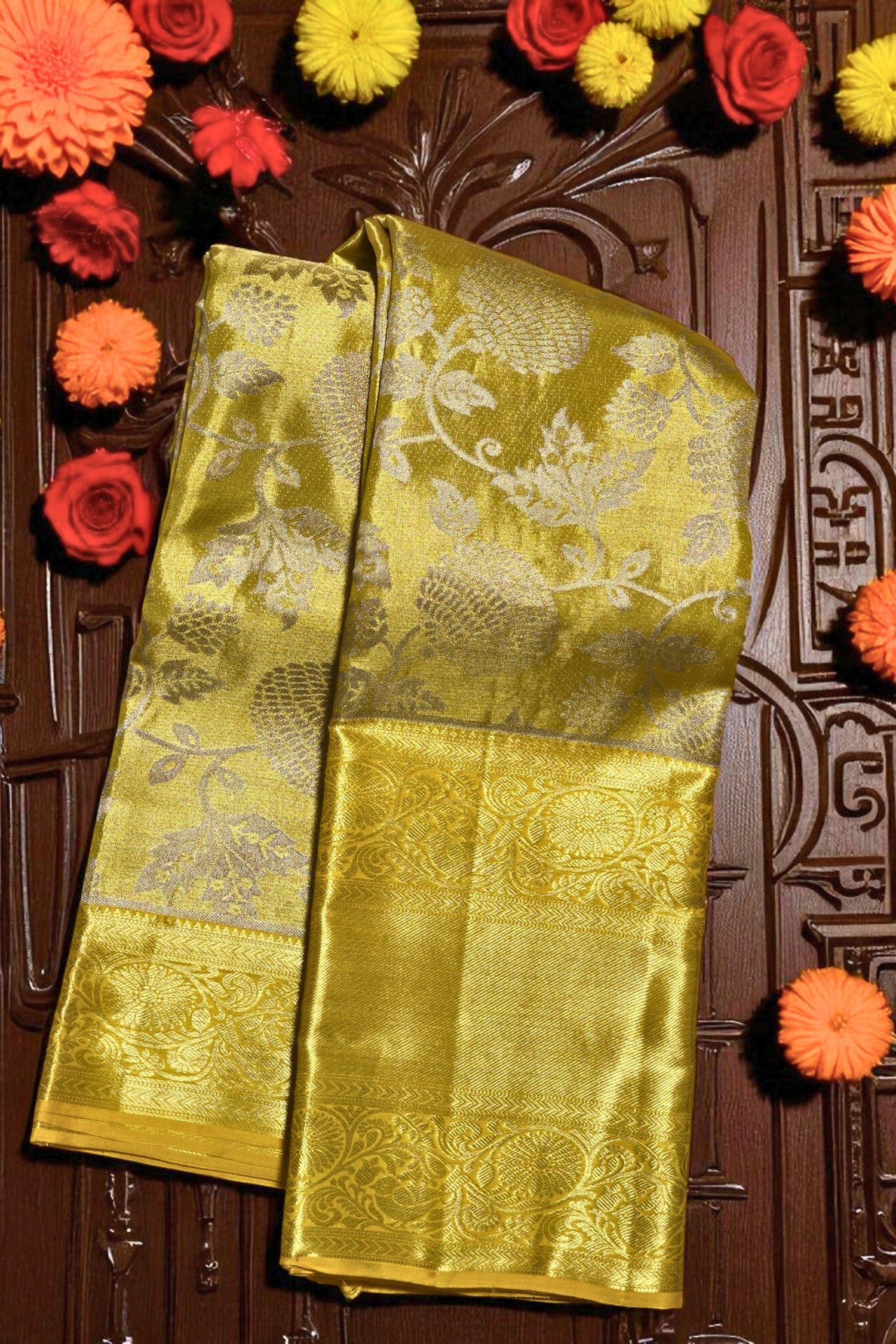 Yellow saree with floral patterns on a wooden background with flowers around