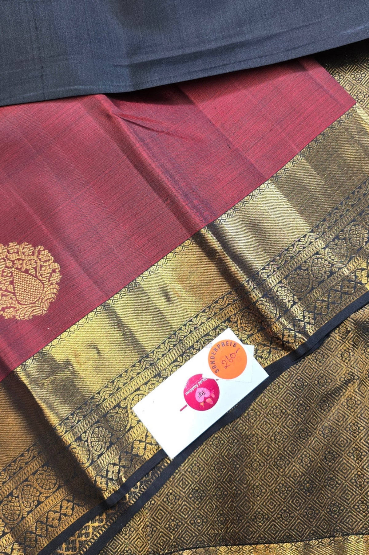 Maroon and gold saree with a visible brand label