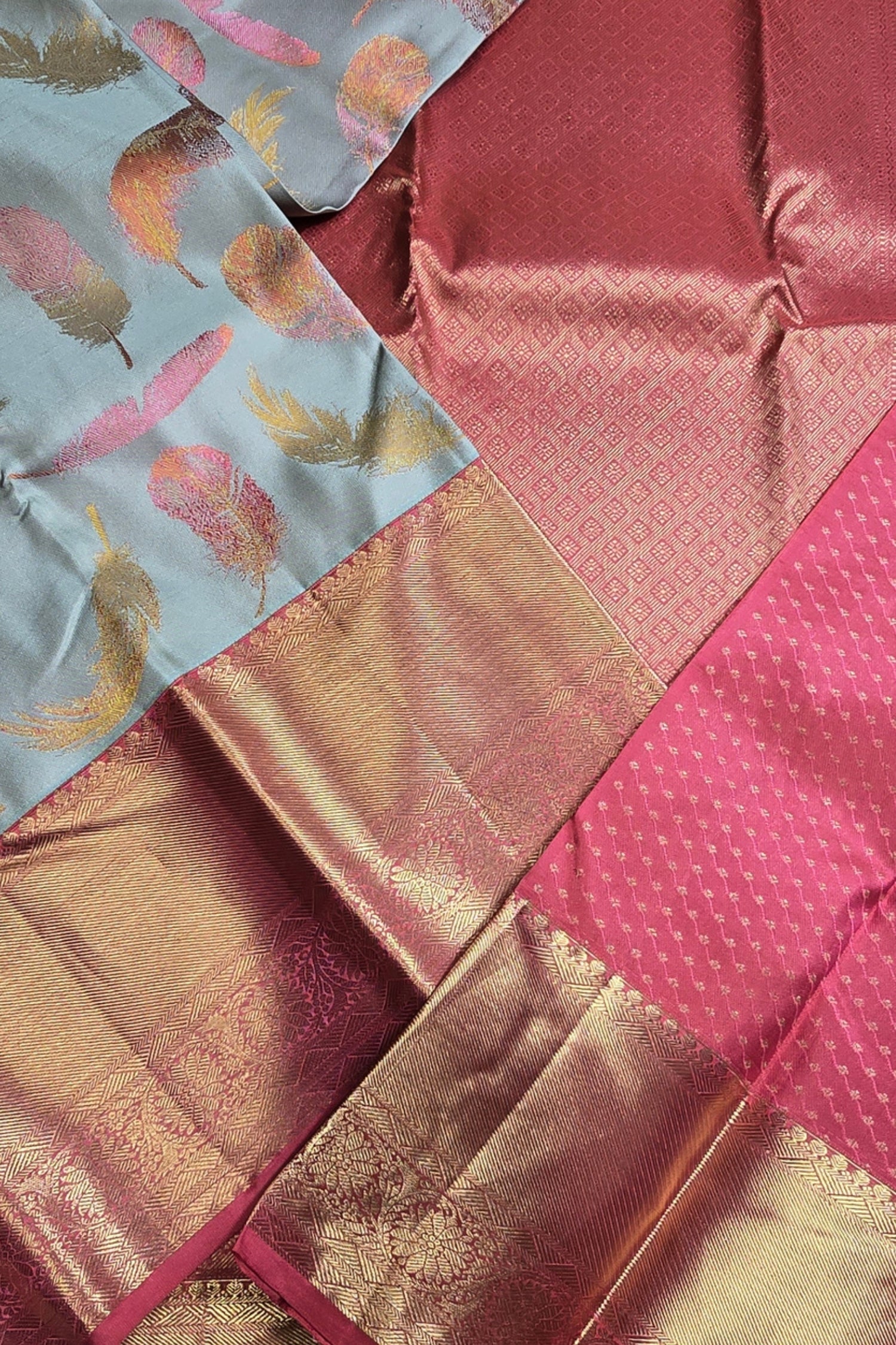 Close-up of a fabric with pink, gold, and multicolor patterns.