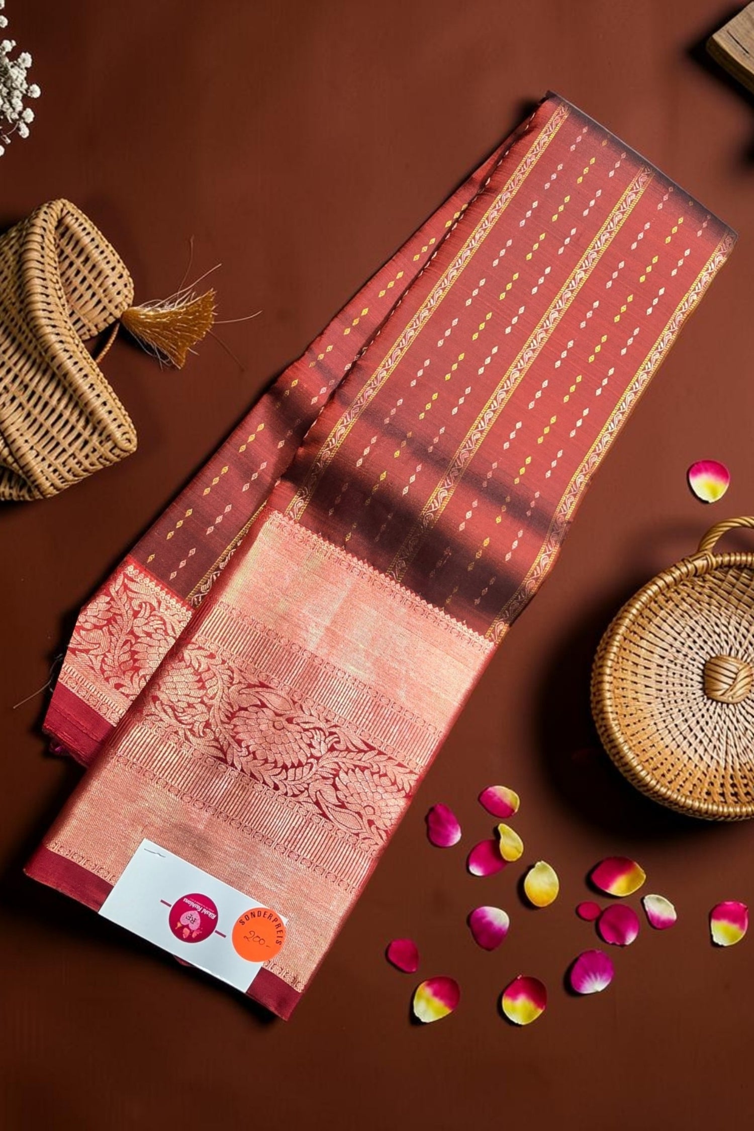 Red and gold saree with decorative elements on a brown background