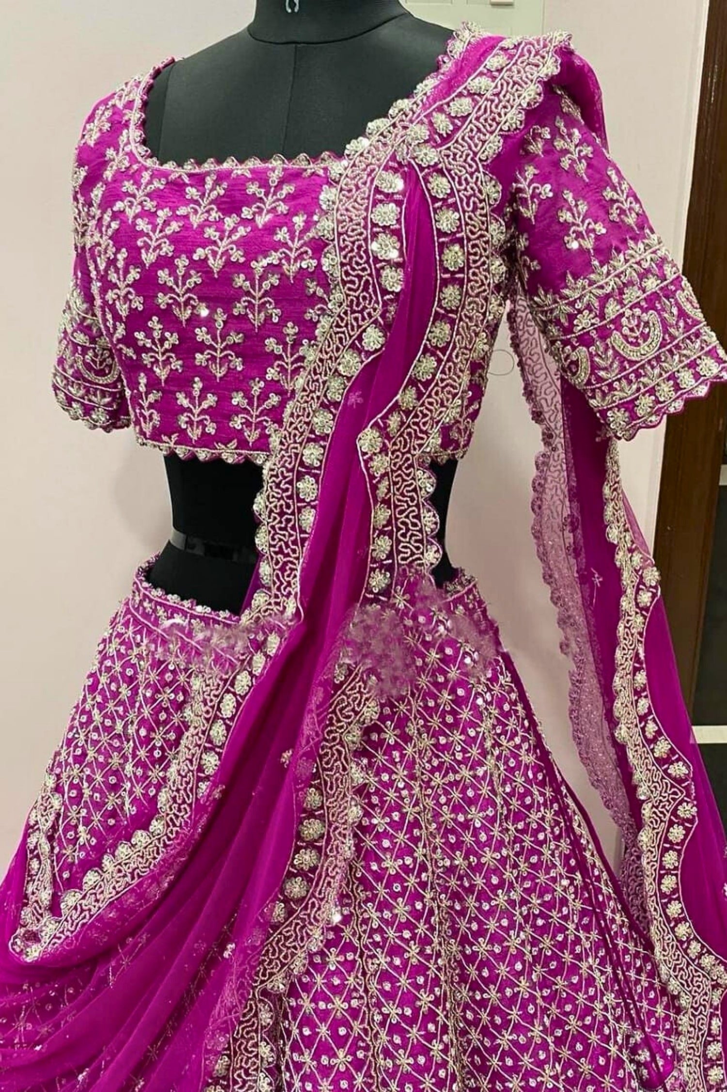 Purple embroidered traditional outfit on a mannequin against a white wall.