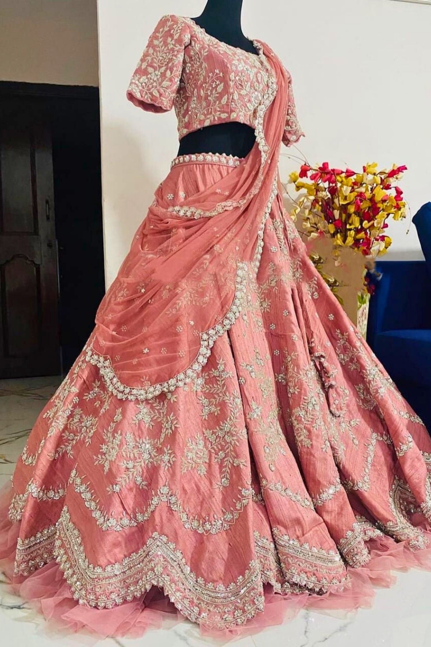 Pink embroidered traditional outfit on a mannequin with a blurred background