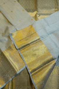 Light sage green silk saree with wide ornate gold zari border elegantly displayed.