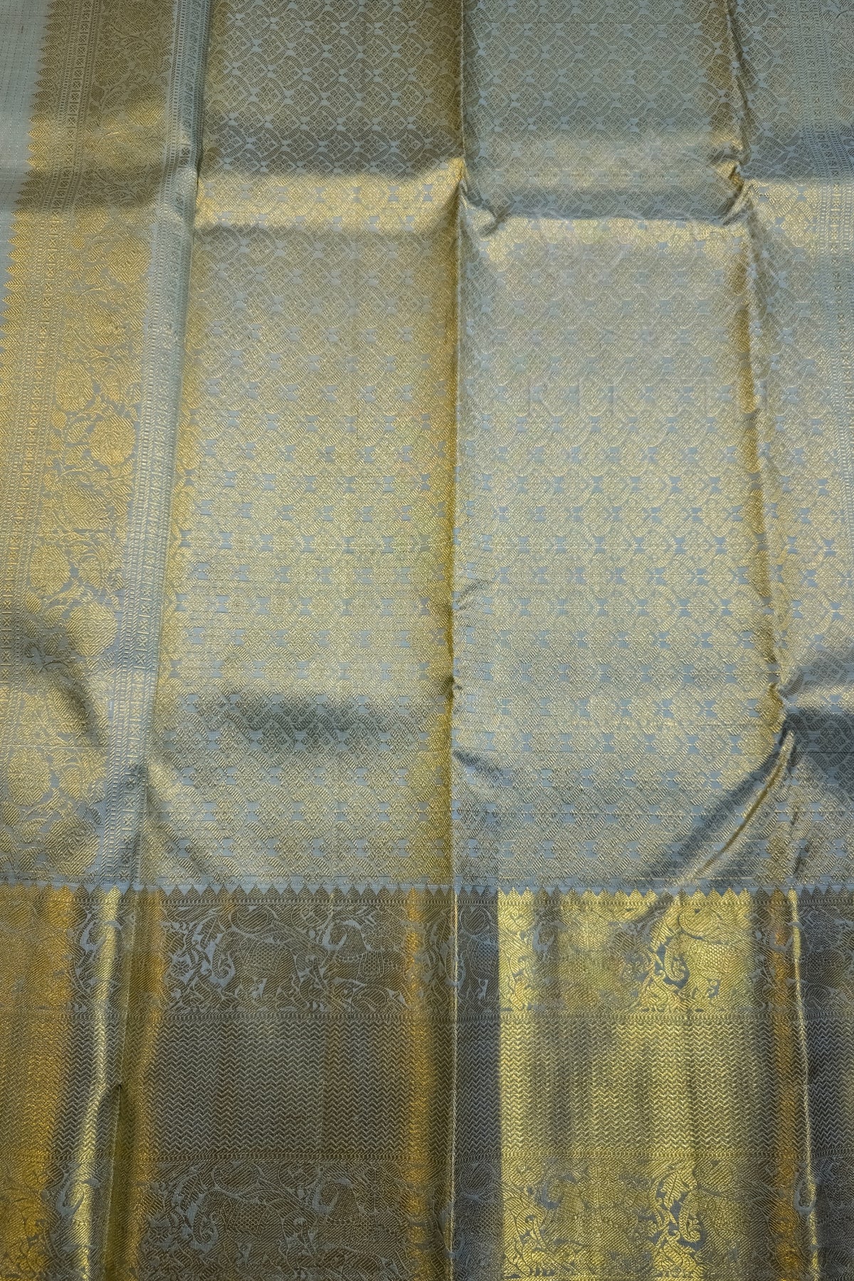 Light sage green silk saree with wide ornate gold zari border in intricate design.