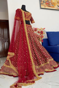 Red and gold embroidered lehenga on a mannequin against a white wall.
