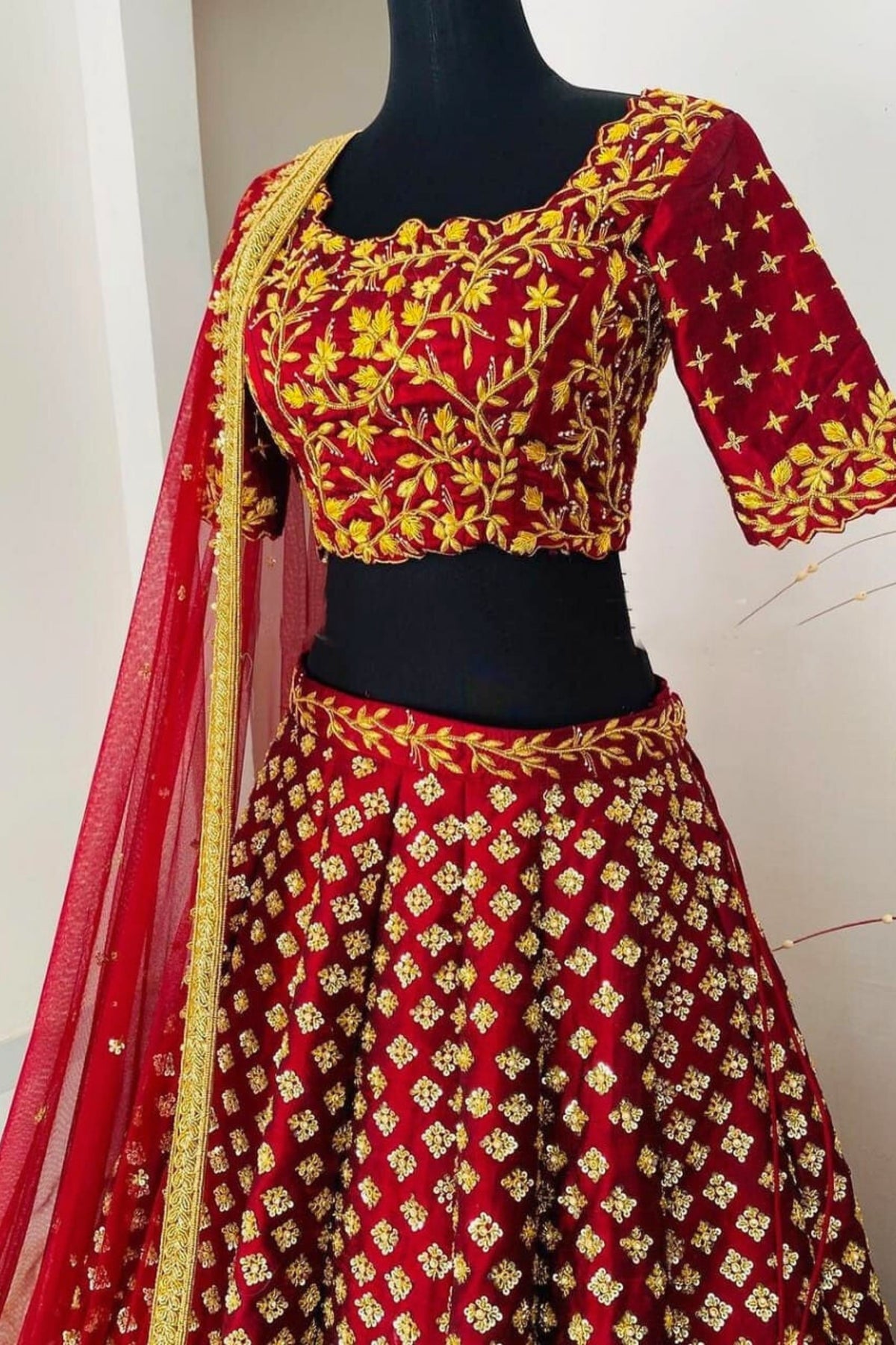 Red and yellow embroidered traditional outfit on a mannequin with a white background