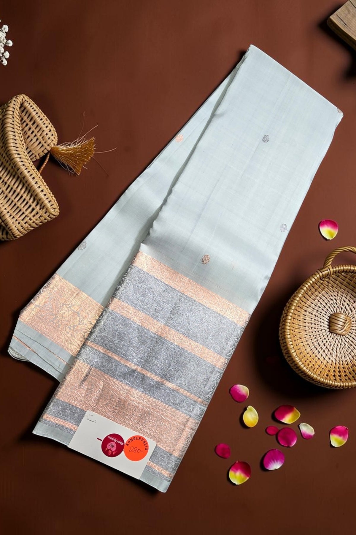 Striped fabric with a woven basket and rose petals on a brown background