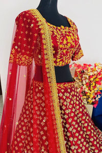 Red and yellow embroidered traditional outfit on a mannequin with flowers in the background