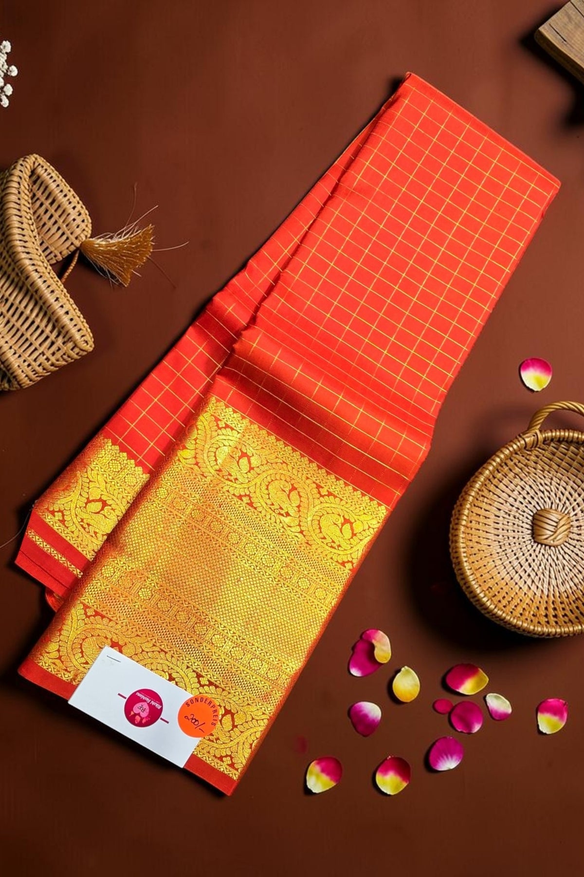 Red and gold fabric with a woven basket and rose petals on a brown background