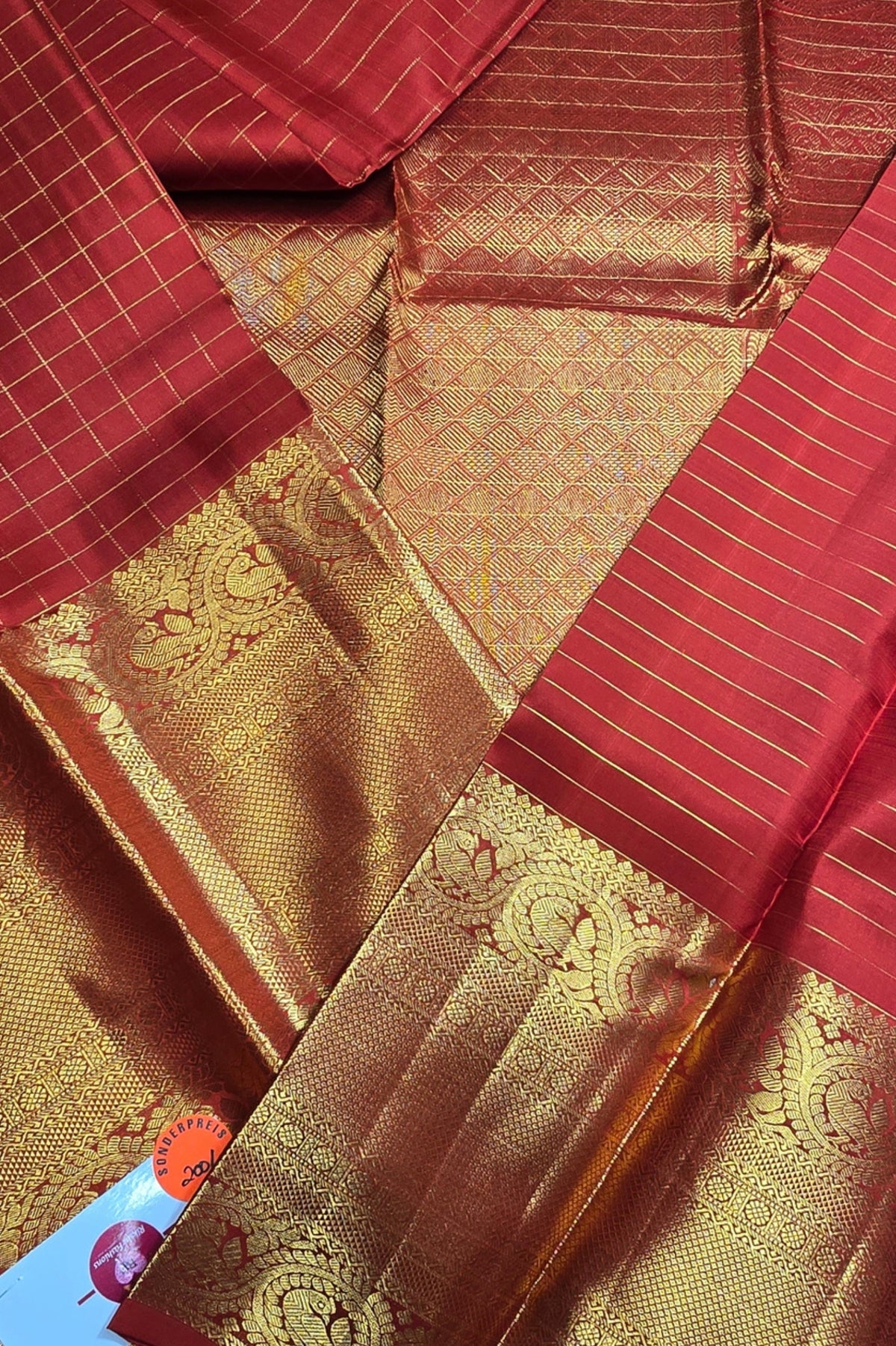 Red and gold saree fabric with intricate patterns