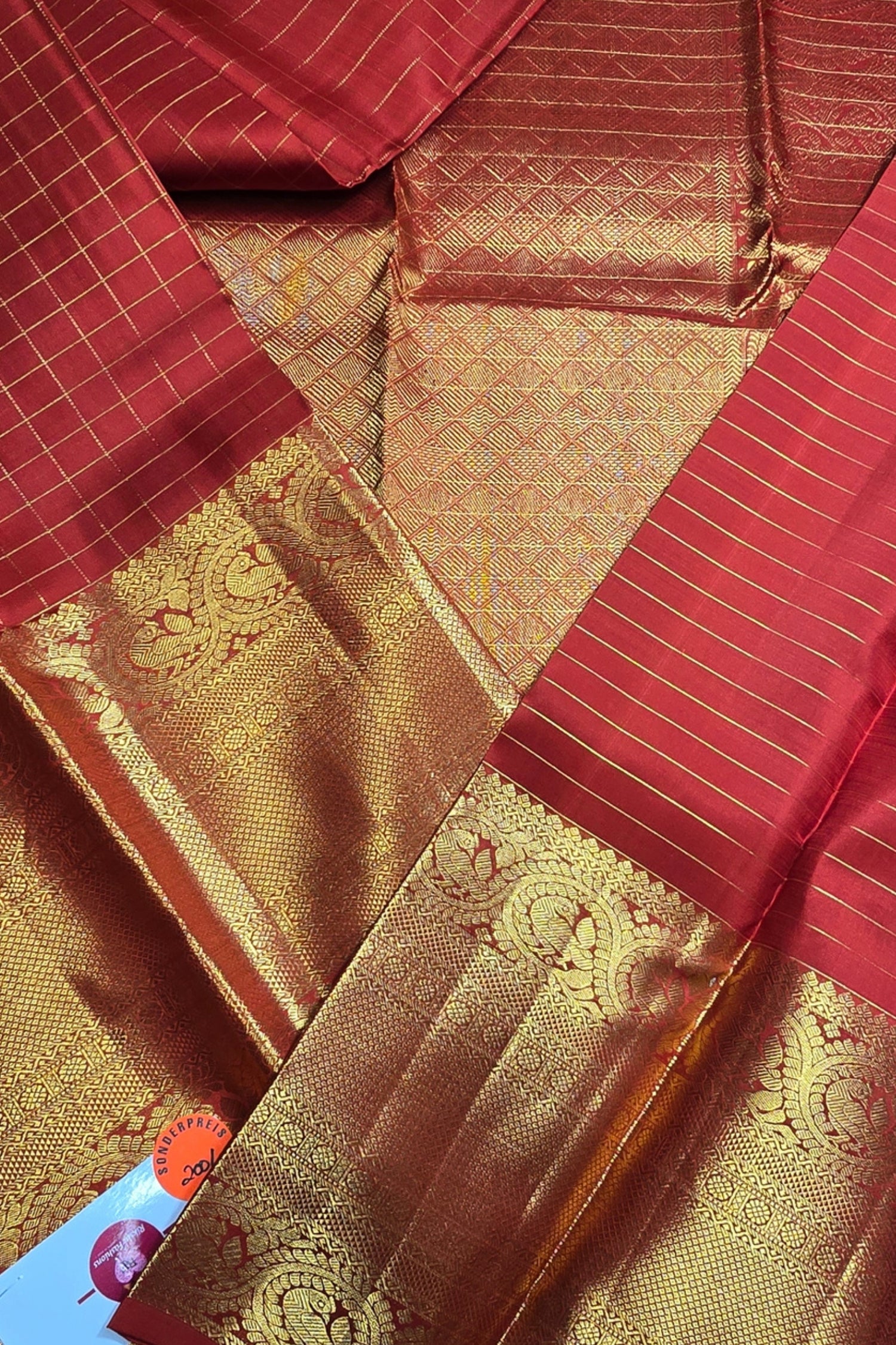 Red and gold saree fabric with intricate patterns