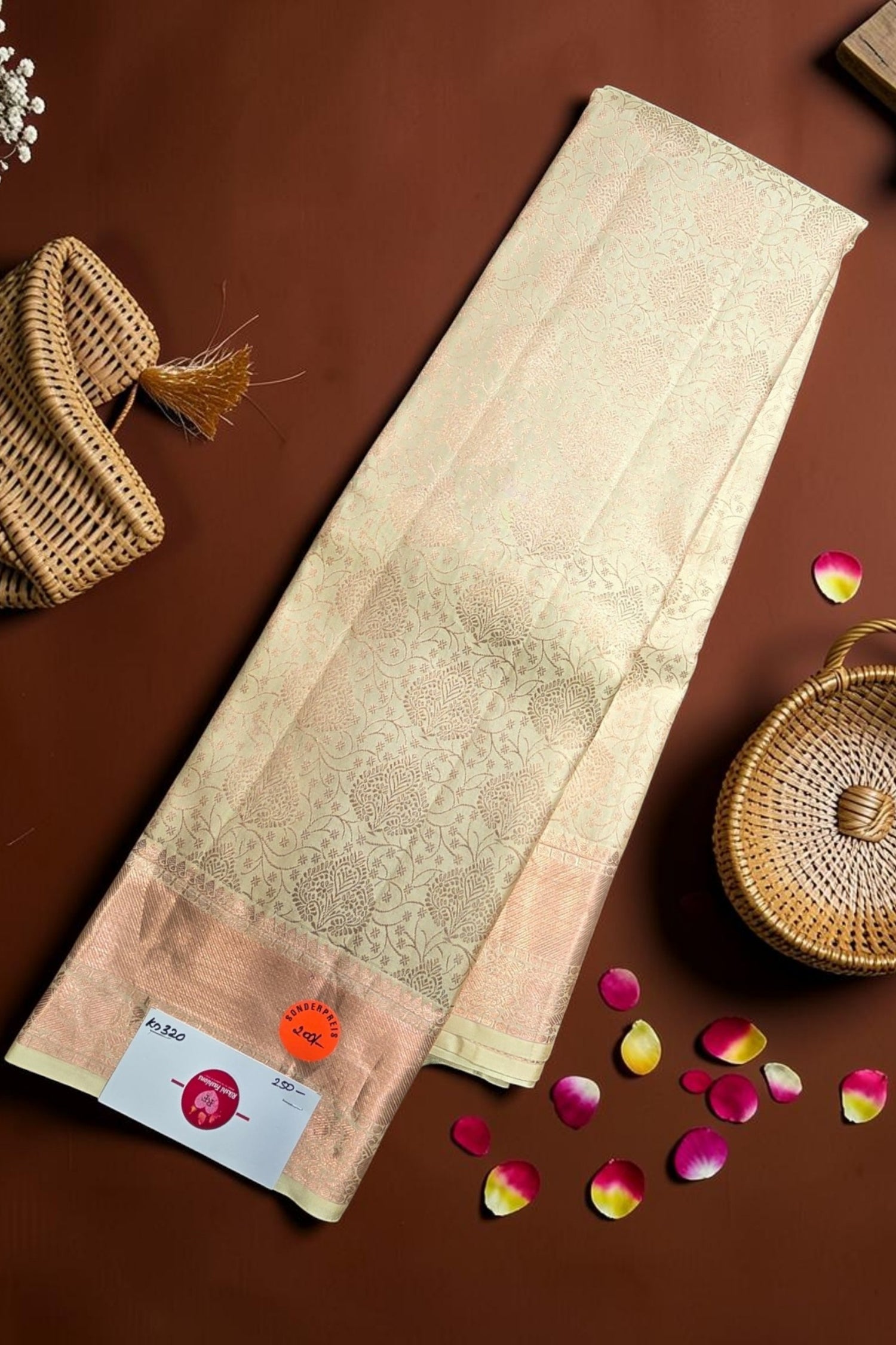 Beige saree with a woven pattern on a brown background with decorative elements.