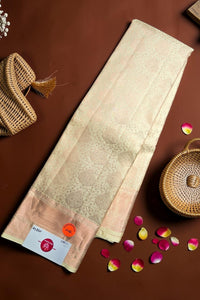 Beige saree with a woven pattern on a brown background with decorative elements.