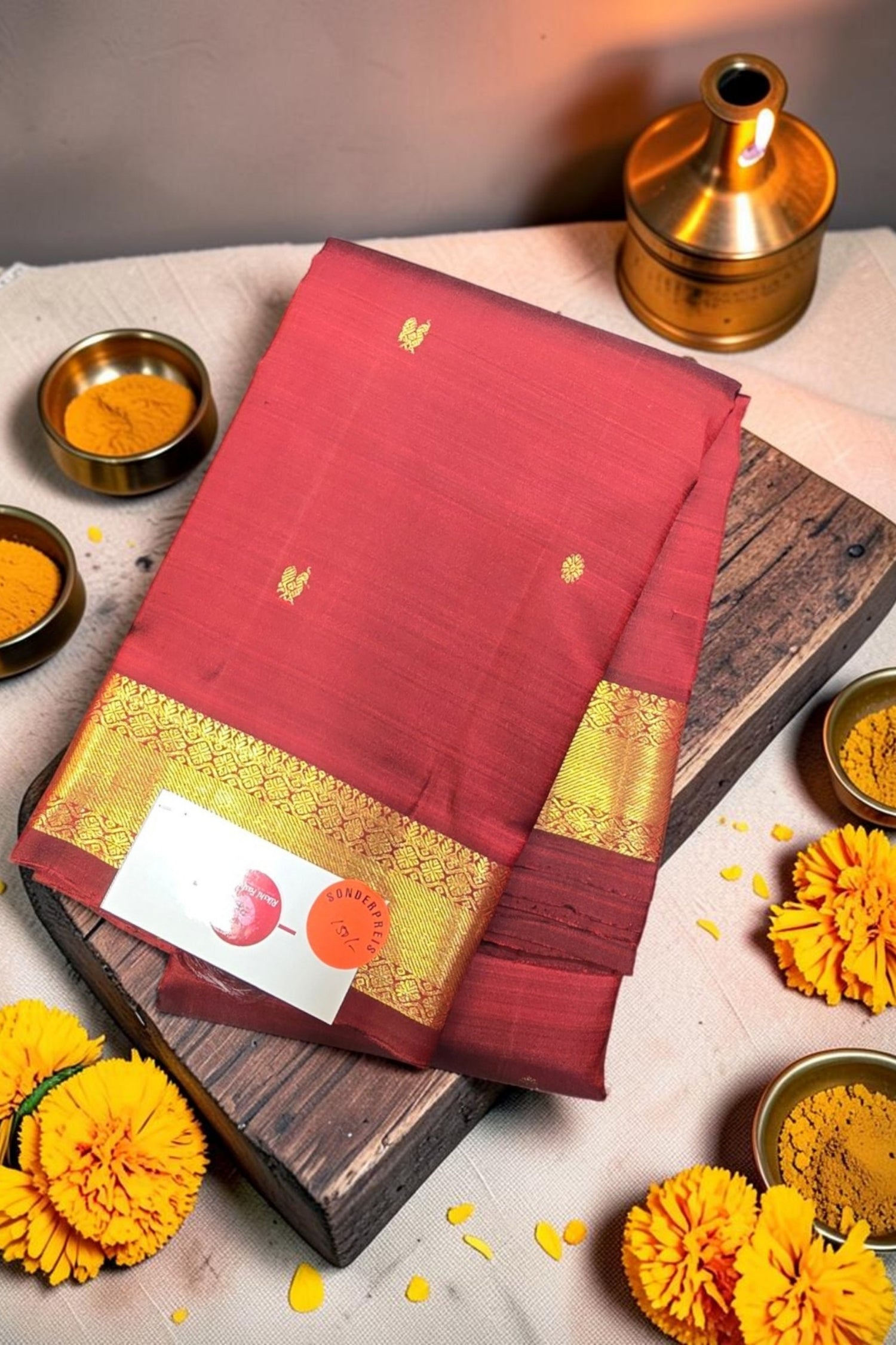 Red saree with gold border on a wooden board with decorative elements
