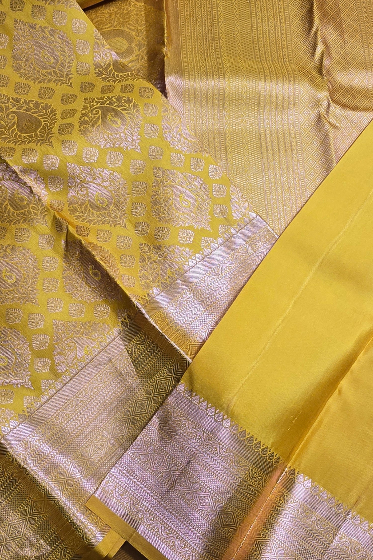 Close-up of a yellow fabric with intricate patterns and borders