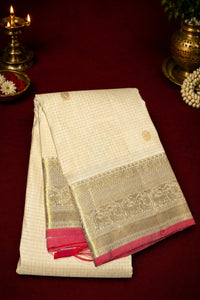 White saree with gold border and pink fabric on a dark red background
