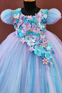 Pastel-colored dress with floral and butterfly decorations on a mannequin against a brown background.