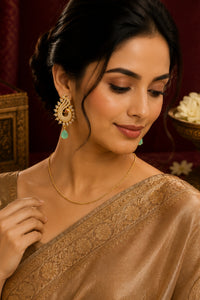 Woman wearing traditional jewelry including earrings and a necklace, with a blurred background.