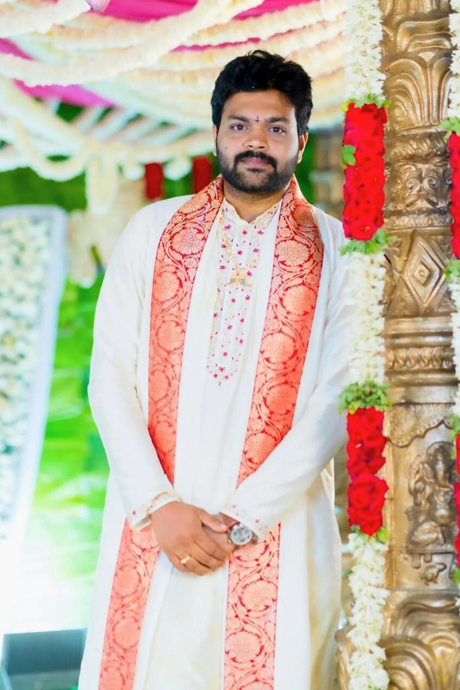 Man wearing a traditional outfit with a decorative background