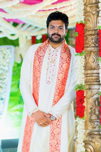 Man wearing a traditional outfit with a decorative background
