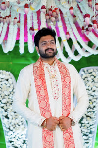 Man wearing a traditional outfit with a decorative background