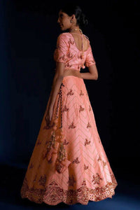 Woman wearing a pink embroidered traditional outfit against a dark background