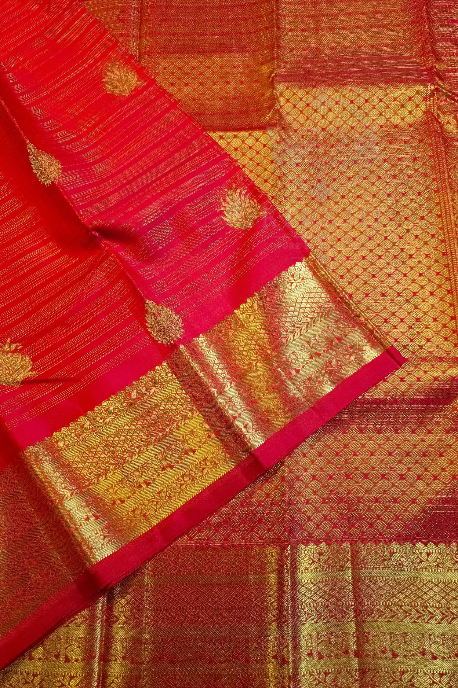 A close-up of a red and gold Banarasi silk saree, showing the vibrant red body with gold zari woven floral motifs and a wide ornate gold border.