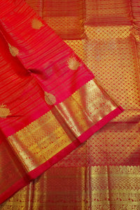 A close-up of a red and gold Banarasi silk saree, showing the vibrant red body with gold zari woven floral motifs and a wide ornate gold border.