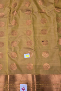 Green fabric with gold circular patterns and a brand label.