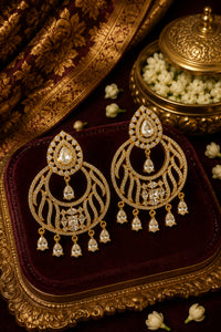 Gold earrings with clear stones on a decorative box