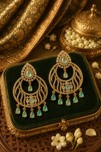 Ornate earrings with green gemstones on a decorative box