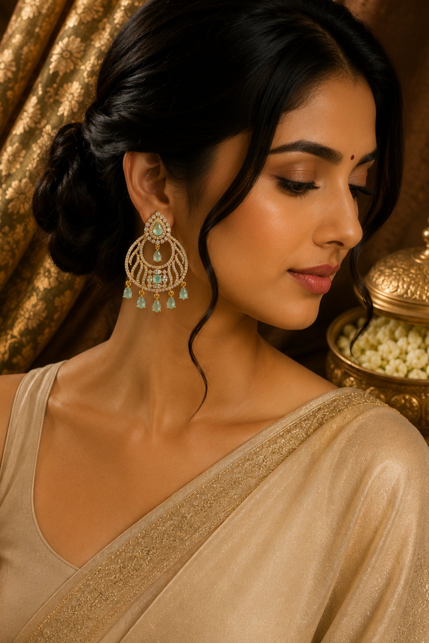 Woman wearing a beige saree with gold details and large earrings against a gold background
