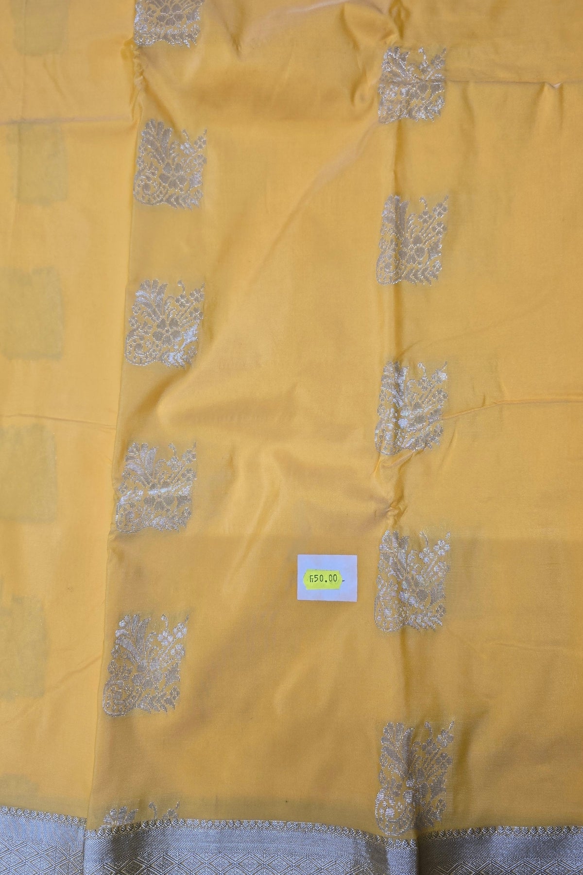 Yellow fabric with silver patterns and a visible brand label.