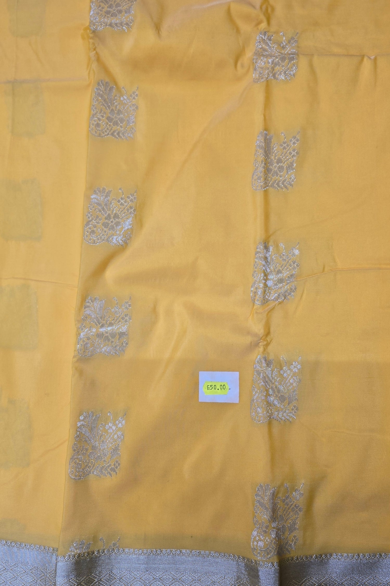Yellow fabric with silver patterns and a visible brand label.