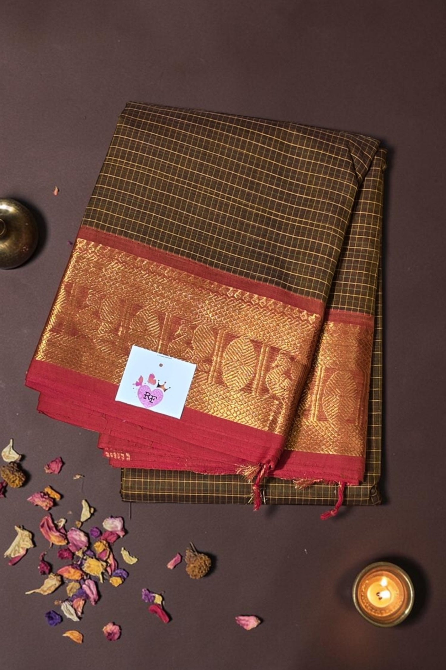 Brown and red saree with gold border on a dark background
