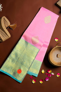 Two traditional sarees with pink and green patterns on a brown surface with decorative elements.